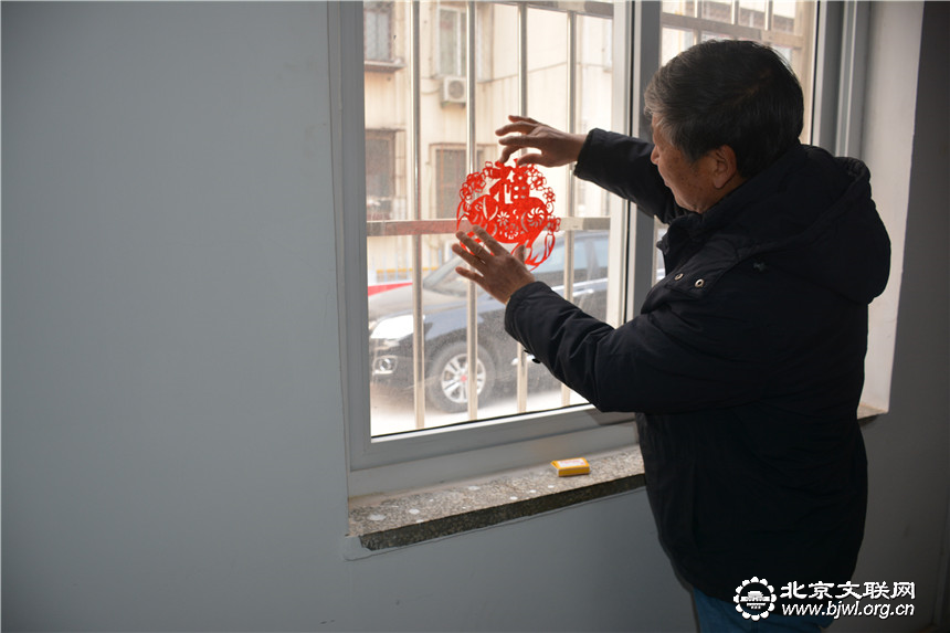 5-艺术家将剪好的窗花贴在窗户上欣赏（段计龙摄）